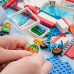 A child holding a lego clown minifigure while building a Lego se